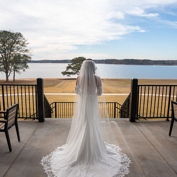 A bride looks out to West Point Lake at her wedding at Oakfuskee Conservation Center.