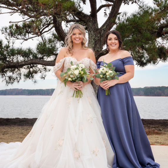 A bride and her bridesmaid pose in front of The Special Tree at Oakfuskee Conservation Center.